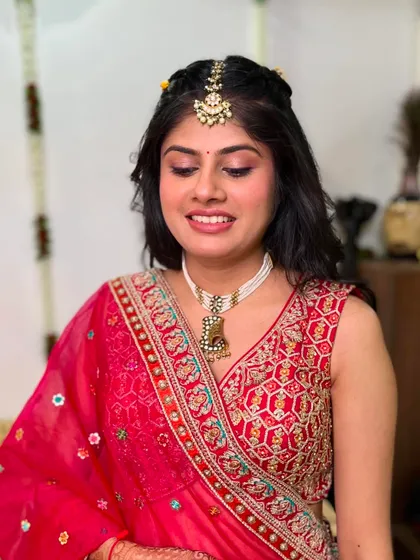 A vibrant and traditional look for a pre-wedding ceremony. The pink and red outfit is paired with a classic makeup look featuring a maang tikka and soft glam eyes.