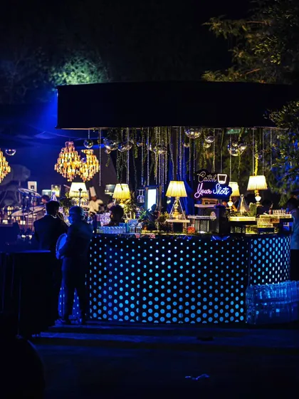 A full view of the quirky, polka-dotted bar under the night sky, surrounded by guests enjoying the party.