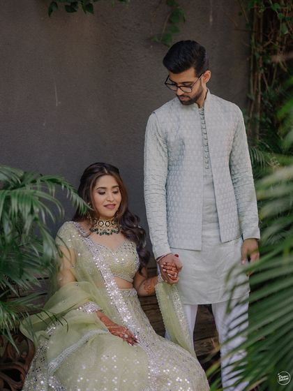 A sweet, gentle moment where the groom holds the bride's hand. This shot from their Mehendi ceremony focuses on the small gestures of love and support between a couple.