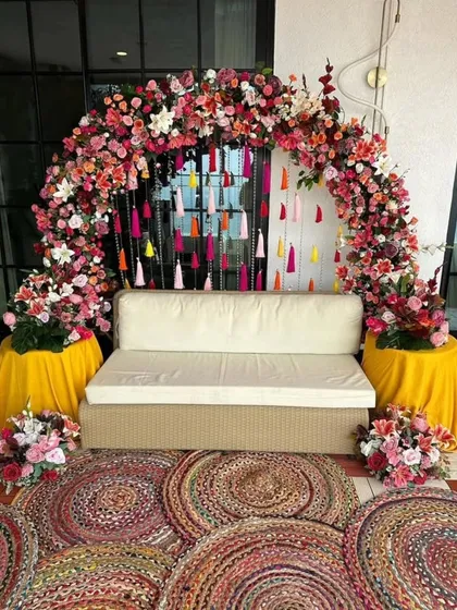 This colorful Mehendi seating area features a lush floral arch bursting with pink and white flowers. I added hanging tassels in various bright colors to create a fun and festive photo corner for the bride and her guests.