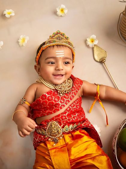 The playful side of a little deity. This overhead shot captures the baby's happy and relaxed mood during the traditional Karthikeya-themed photoshoot.