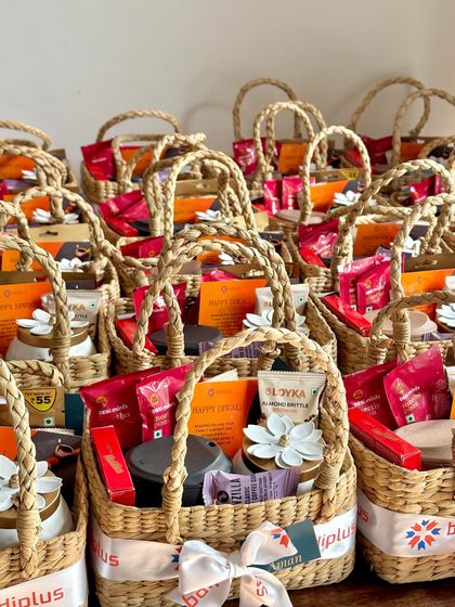 We love the joy of executing a large corporate Diwali order. These beautiful cane baskets were customized for a client and filled with a delightful mix of items, including a jar candle, tumbler, lotus tealight holder, and various gourmet snacks.