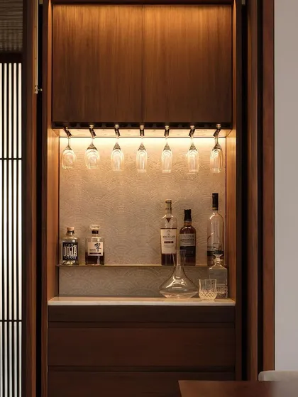 This custom-designed bar unit for our Altamount Road apartment is a perfect example of integrated design. The warm, concealed LED lighting highlights the textured backdrop and glassware, while the rich wood cabinetry provides seamless, elegant storage.