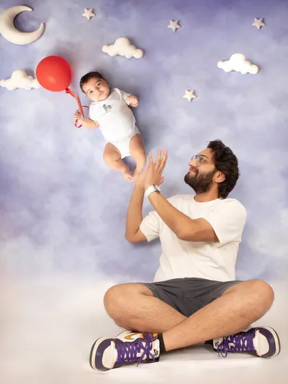 A father's love is a powerful thing. This whimsical portrait captures a sweet, interactive moment between dad and his "floating" baby, creating a picture full of imagination and joy.