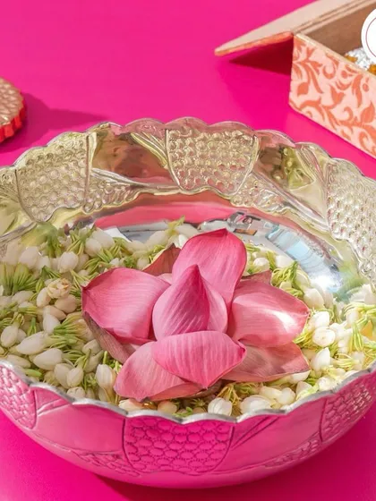 A luxurious pure silver bowl with intricate carvings, filled with fresh jasmine flowers and a lotus bud. A beautiful and fragrant gift.