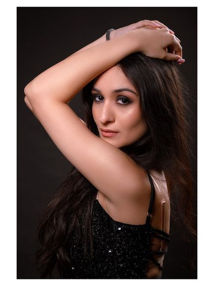 A glamorous studio portrait in a sparkling black dress. The model's pose is elegant and sophisticated.