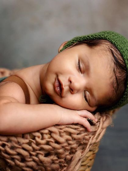 Look at that sweet smile! This little one is dreaming peacefully in a cozy basket. This shot was part of a sibling session, and he was so calm and happy.