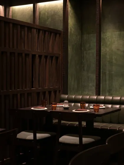 Another view of the dining area at Otra. The combination of dark wood, green leather banquettes, and textured walls creates a rich, layered interior that feels both modern and timeless.