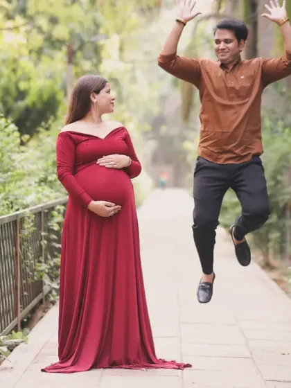 A fun and candid outdoor shot capturing the dad-to-be jumping for joy while the mom-to-be watches with a smile. We love capturing these playful moments.