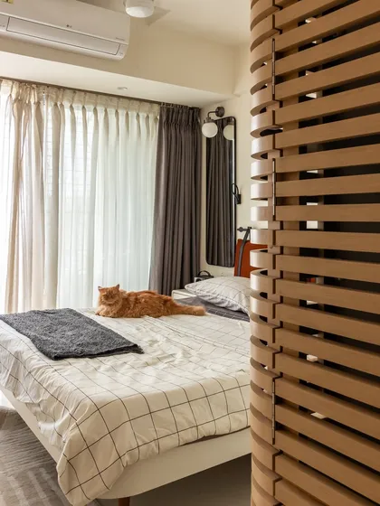 The bedroom, complete with its most important resident, Penny the cat. The wooden slat partition adds a touch of texture and creates a sense of separation without closing off the space.