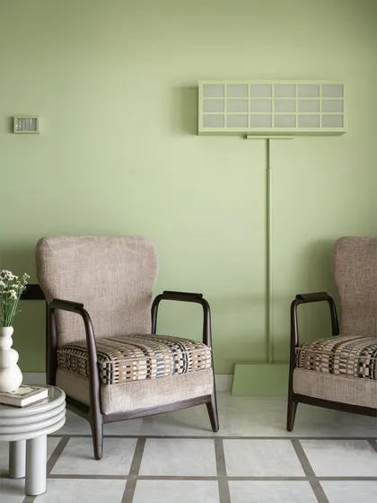 A pop of apple green on the wall marks the arrival at our 'Gingham Dreams' project. The sitting area features a duo of armchairs and a unique light-box style floor lamp that we had fixed to the wall per our client's request.