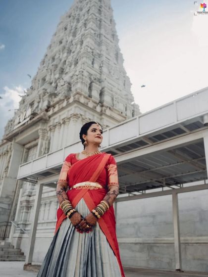 A powerful, low-angle shot of the bride in front of a temple gopuram. This perspective adds a sense of grandeur and majesty to her traditional look.
