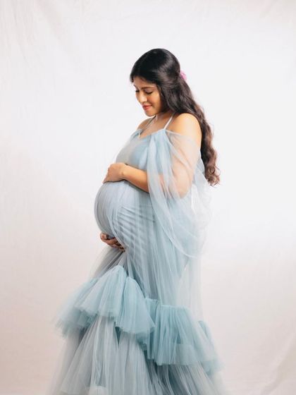 A profile shot of the Winter gown, showing how it drapes beautifully over the baby bump. The off-shoulder sleeves add a soft, romantic touch.