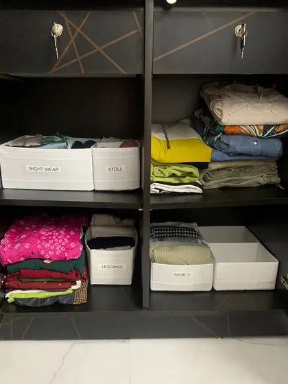 Labeled bins are a simple but powerful tool for maintaining order. Here, "Night Wear," "Stoll," "Leggings," and "Shorts" each have their own clearly marked home.