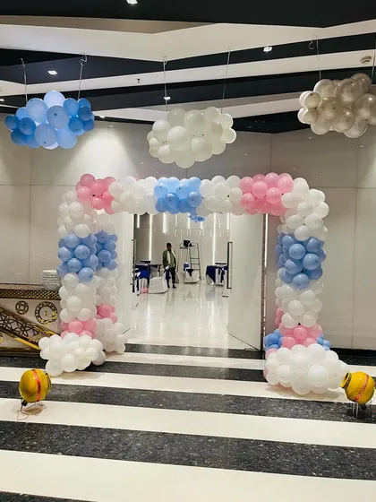 An entrance arch and ceiling decorations with balloon clouds in pastel colors, perfect for a large event hall.