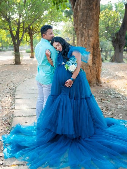 A tender moment between a couple during their outdoor maternity shoot in a beautiful blue gown.
