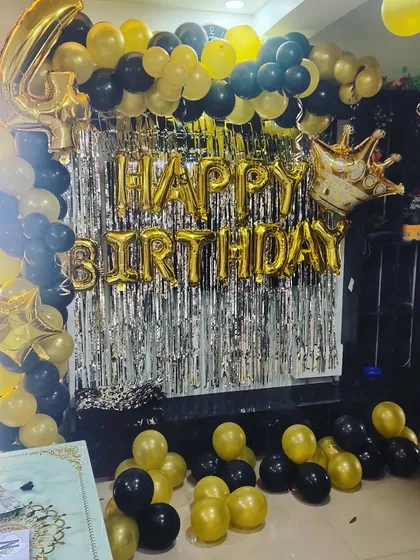 A 4th birthday party with a black and gold theme, featuring a full balloon arch and a large foil number.