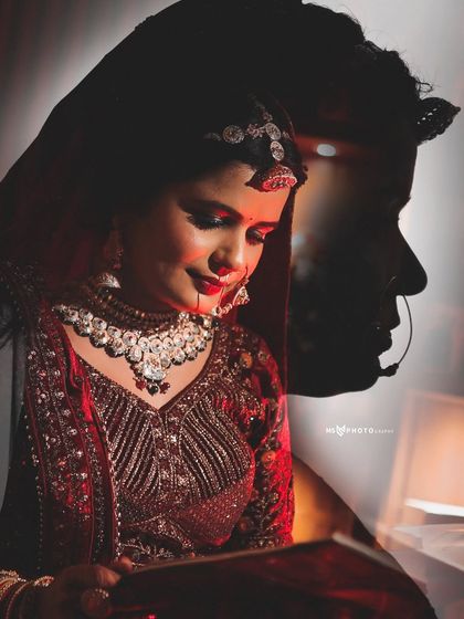 A creative double exposure portrait of the bride in her red wedding attire. Her thoughtful expression is layered with her silhouette, adding an artistic and emotional depth to the photograph.