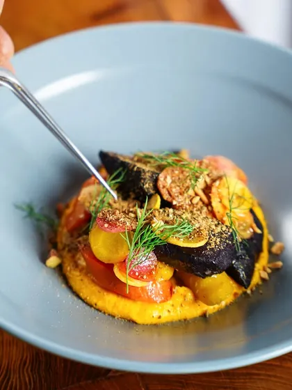A chef's tweezers delicately placing a garnish on a gourmet dish. This close-up shot highlights the precision and artistry involved in fine dining plating.
