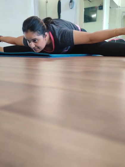 A student demonstrates a full front split with a forward bend (Upavistha Konasana). This pose is the result of consistent practice, focusing on opening the hips and stretching the hamstrings.