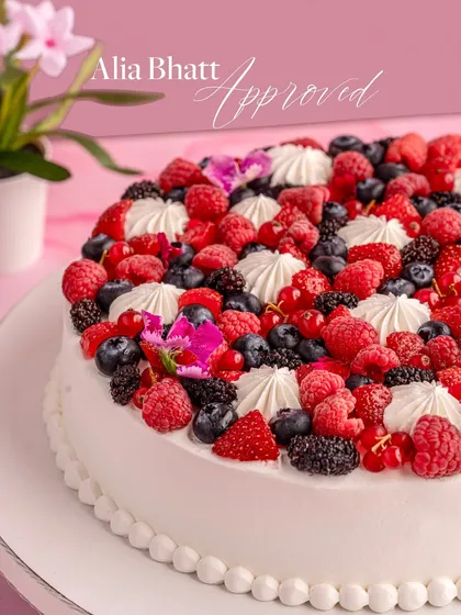 A close-up of the "Alia Bhatt Approved" Milk Soaked White Chocolate Mousse Cake. It's crowned with plump berries and dollops of cream.