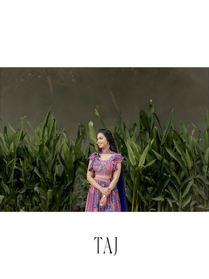A serene and beautiful portrait of the bride against a wall of lush green leaves. The natural backdrop makes the colors of her traditional outfit pop.