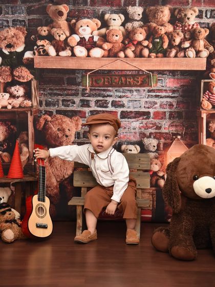 Strumming a little tune for his teddy bear friends. Interactive props like this mini guitar make the photoshoot a fun experience for the child.