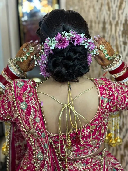 A detailed shot of a beautiful bridal bun adorned with fresh purple and white flowers. This showcases the hairstyling skills that complete the perfect bridal look.