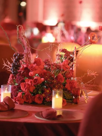 The warm glow of candles reflecting off the red velvet chairs creates an intimate and luxurious atmosphere.