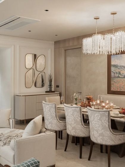 This dining space combines classic English elements with modern comfort. A crystal chandelier hangs above a formal dining table, while a comfortable bench and patterned chairs create an inviting setting for family meals and gatherings.