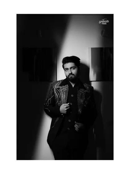 A classic black and white portrait of the groom. The strong shadows and his sharp attire create a timeless, sophisticated look, like a still from a classic Hollywood film.