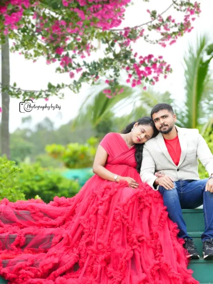 A romantic couple's portrait on green steps, with the mother-to-be in a red ruffled gown.