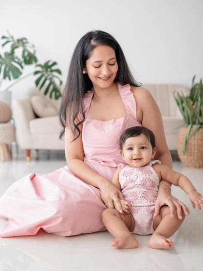 A mother and daughter sitting together in matching pink outfits.