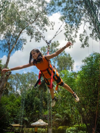 A young adventurer enjoying the Superman Swing, flying through the air with arms outstretched.