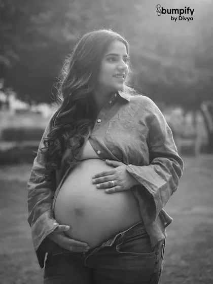 A stunning solo black and white portrait of the mom-to-be. Her casual, unbuttoned shirt and jeans create a raw, beautiful, and modern look.