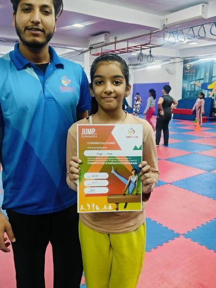 This gymnast proudly holds her "JUMP" certificate, showing her progress.