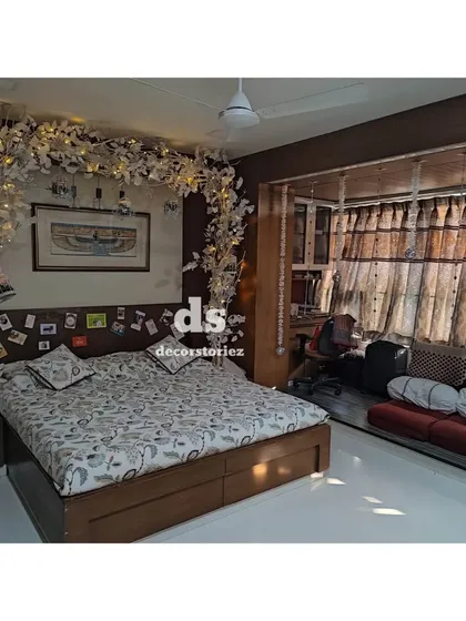 A wider perspective of the white floral arch decoration for a 25th anniversary. This shows how the decor element transforms the entire bedroom, making it feel special and luxurious.