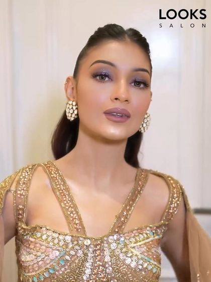 A high-fashion party look with a sleek, high ponytail. The makeup is sharp and defined, with a unique mauve-toned lipstick and shimmering eyeshadow that catches the light.