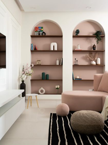 This living room from my "Casa Curva" project features soft, curved furniture and arched niches for display. The dusty pink sofa and matching wall color create a warm, inviting, and cohesive look that is gentle on the eyes.