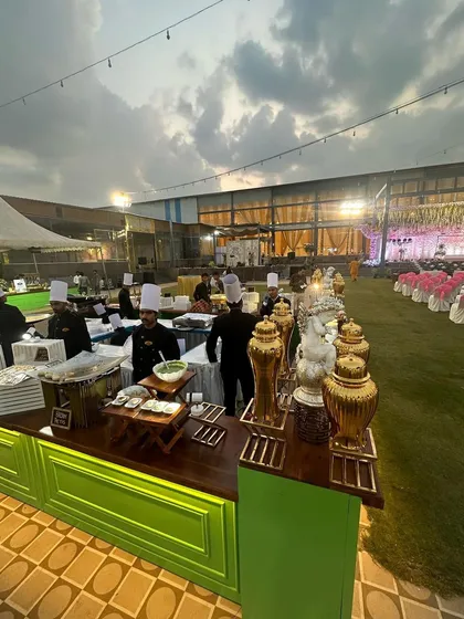 This wide-angle shot captures the scale of our catering setup for a large outdoor wedding. You can see multiple live cooking stations ready for service, staffed by our team of professional chefs against the backdrop of the elegant venue.