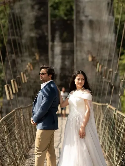 Our white gown with an attached veil trail offers a modern twist on a classic bridal look. It's perfect for pre-wedding shoots on location, like this scenic bridge.