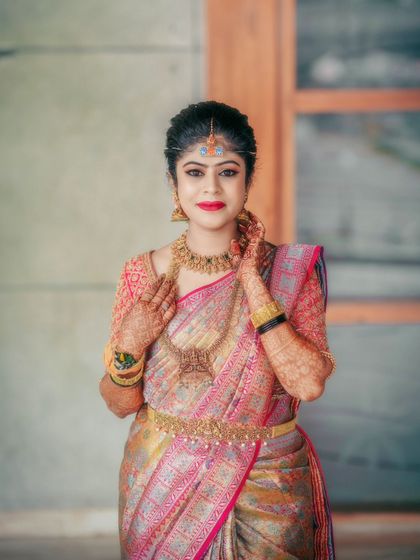 A beautiful portrait of a bride in a traditional pink and gold saree.