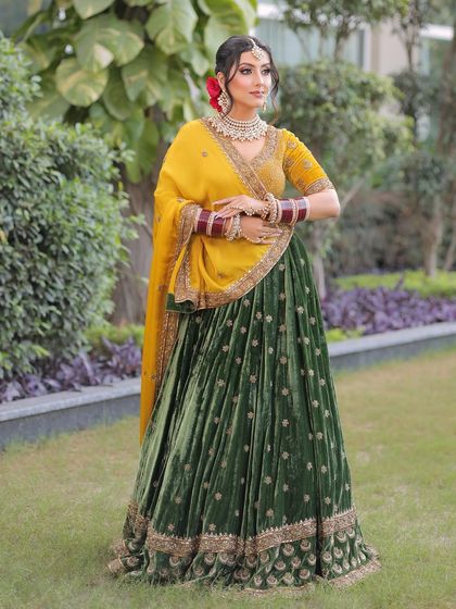 A full view of this stunning bridal ensemble. The makeup is kept elegant and timeless, with a focus on a radiant glow that complements the rich velvet and silk of her lehenga.