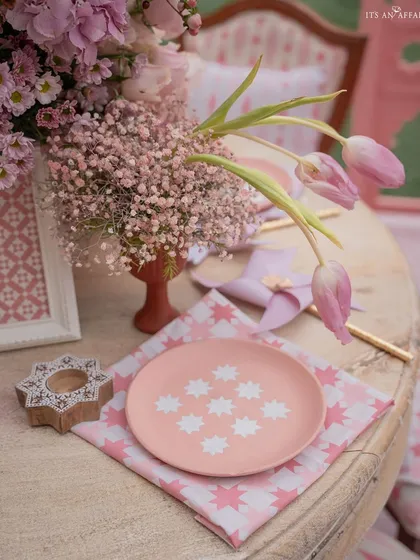 A close-up of the tablescape, featuring a custom-painted pink plate, patterned napkin, and fresh tulips.