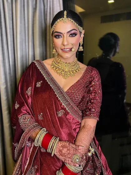 A radiant bride, a vision in every brushstroke. This look in a deep maroon velvet lehenga is all about classic elegance, with defined eyes and a flawless complexion.