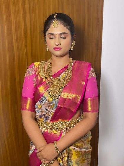 A full view of a bride in her beautiful saree. The makeup is designed to harmonize with the vibrant colors and heavy gold jewelry.
