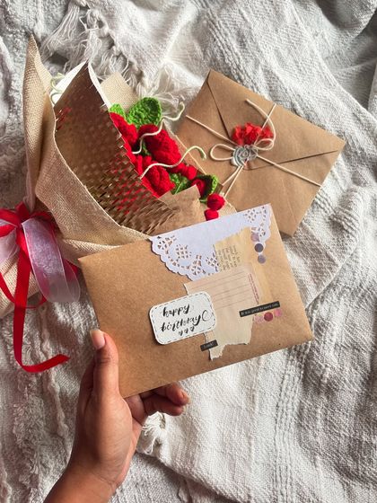 A close-up of the "Happy Birthday" card that goes with the crochet rose bouquet. The rustic, handmade feel is consistent across all the items in the set.