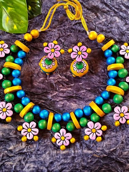This exclusive floral piece is perfect for a haldi or mehendi function. It combines pink, green, and blue flowers with yellow and green beads for a truly festive and colorful look.