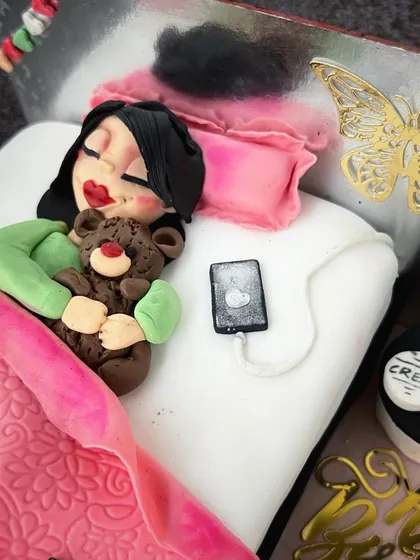 A close-up of the 18th birthday cake, showing the detailed fondant work of the sleeping girl, her teddy bear, and phone.