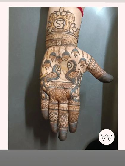 A designer mehndi with two birds under hanging jhumkas (bells).